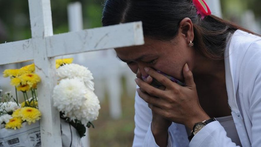 Une femme se recueille durant une cérémonie commémorative en hommage aux victimes du super typhon Haiyan  enterrés dans une fosse commune à Tacloban, dans le centre des Philippines, le 8 novembre 2014
