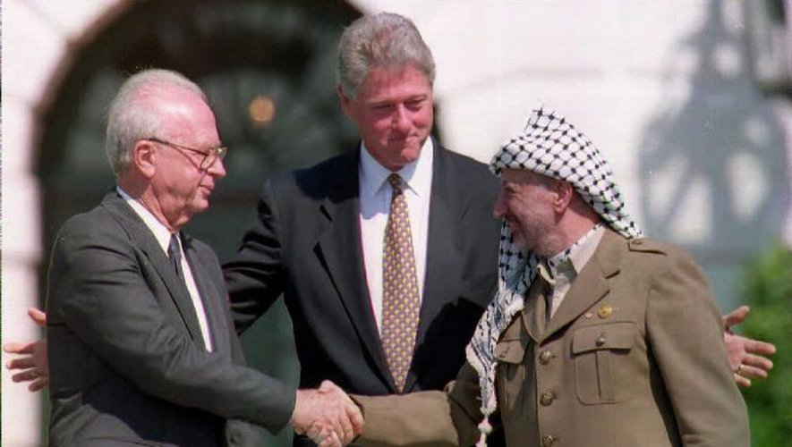 Poignée de mains historique entre le président de l'OLP Yasser Arafat (d) et le Premier ministre israélien Ytzhak Rabin, sous les yeux du président américain Bill Clinton à la Maison blanche, le 13 septembre 2013