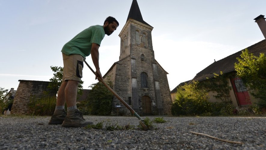 Guillaume Claude, le jardinier en chef du village Saint-Pierre-de-Frugie enlève les mauvaises herbes devant l'église, le 12 septembre 2016.