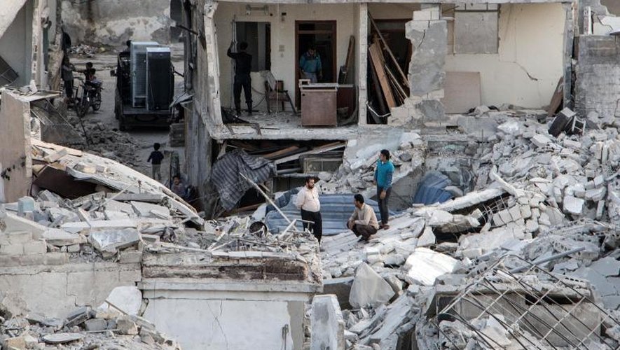 Des habitants sur les ruines de bâtiments détruits par des frappes du régime syrien à Alep, le 28 octobre 2014