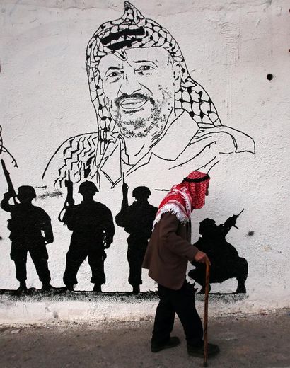 Un vieux Palestinien passe devant un portrait de l'ancien leader Yasser Arafat dans une rue de Ramallah, en Cisjordanie, le 27 octobre 2014