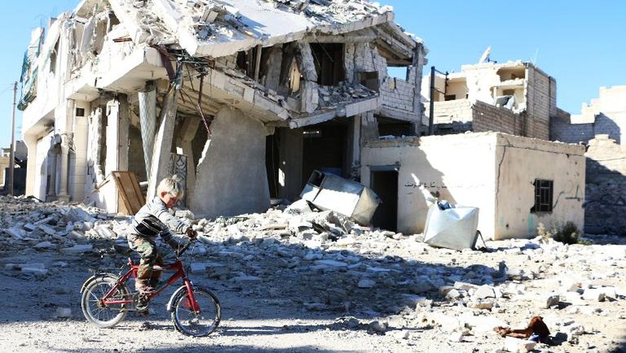 Un garçonnet passe à vélo devant un bâtiment détruit par des bombardements à Alep, dans le nord de la Syrie, le 5 novembre 2014