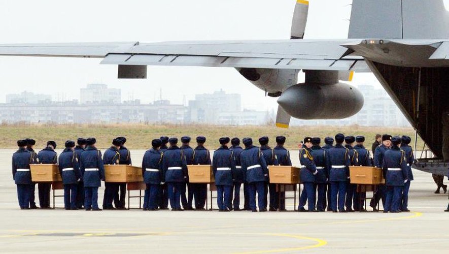 Des soldats ukrainiens s'apprêtent à charger les cinq cercueils contenant les restes des victimes du vol MH17 à bord d'un avion à destination des Pays-Bas, le 8 novembre 2014 à l'aéroport de Kharkiv