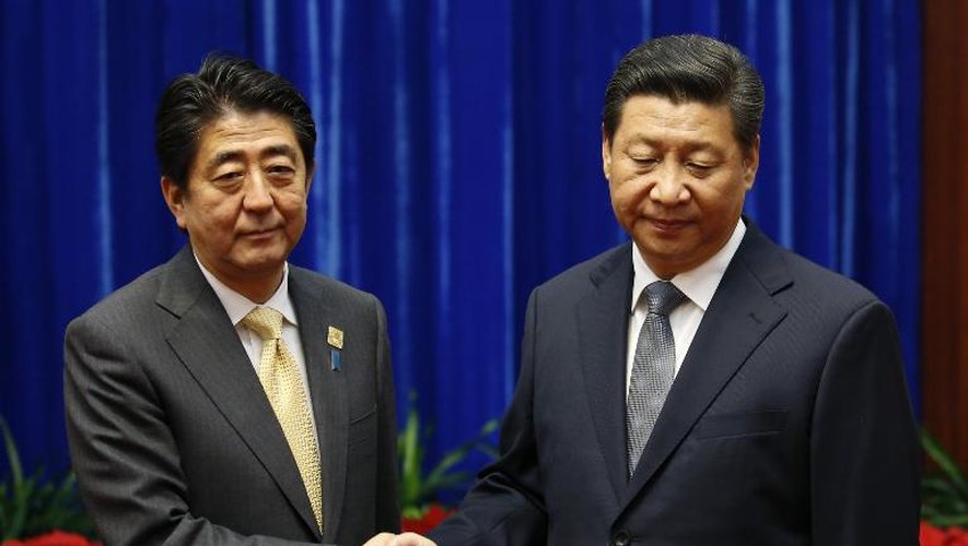 Poignée de mains entre le président chinois Xi Jinping (d) et le Premier ministre japonais Shinzo Abe au Palais du Peuple, en marge du sommet de l'Apec, le 10 novembre 2014 à Pékin