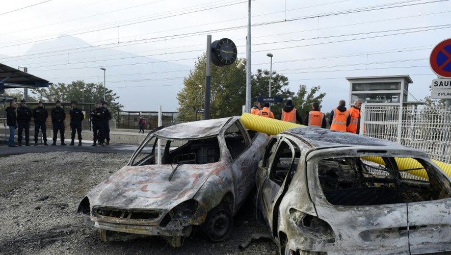 Des gendarmes le 21 octobre 2015 devant des véhicules incendiés la veille lors de violents incidents à Moirans