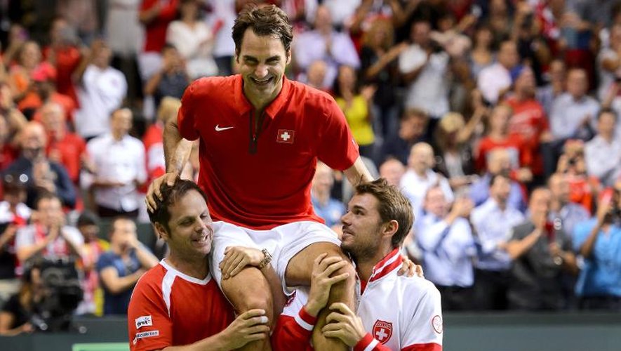Roger Federer porté en triomphe par son coéquipier Stan Wawrinka (d) et le capitaine de l'équipe de Suisse de Coupe Davis, Severin Luthi, le 14 septembre 2014 à Genève