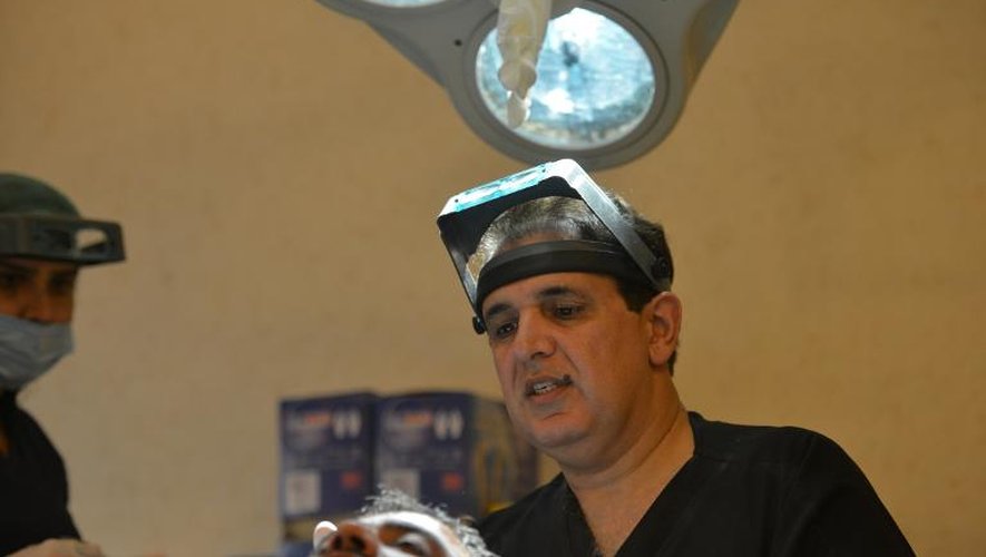 Le docteur pakistanais Humayun Mohmand un pionner dans la greffe de cheveux dans la salle d'opération de sa clinique à Islamabad, le 16 octobre 2014
