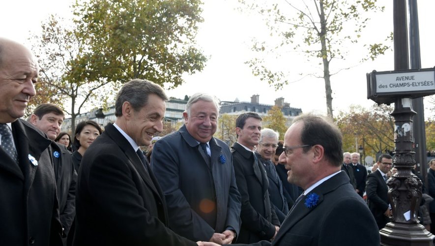 Poignée de mains entre François Hollande (D) et Nicolas Sarkozy, en présence de Jean-Yves Le Drian, Gérard Larcher, Manuel Valls et Claude Bartolone lors de la commémoration de l'amistrice, le 11 novembre 2015 sur les Champs Elysées à Paris