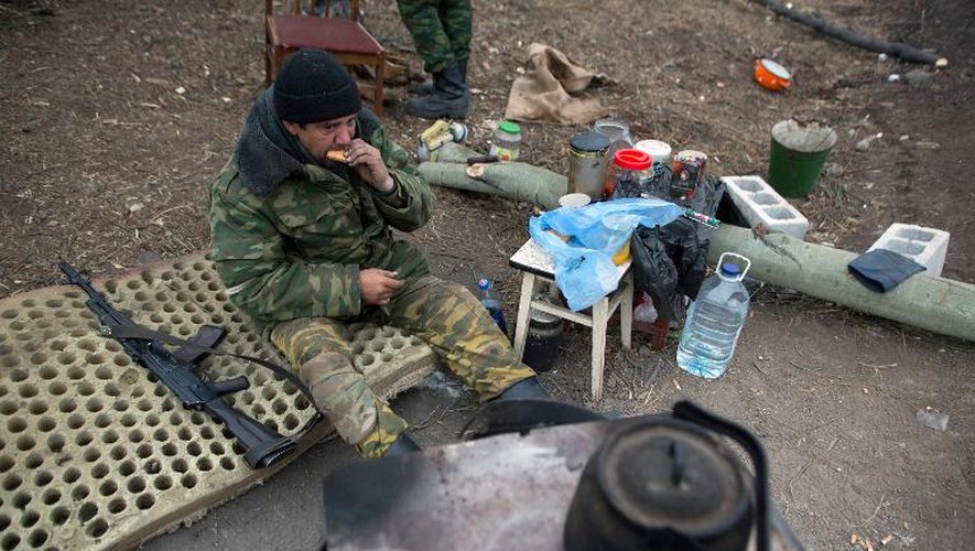 Un rebelle prorusse mange près d'une tranchée dans le quartier d'Oktyaber au nord-ouest de Donetsk, le 13 novembre 2014