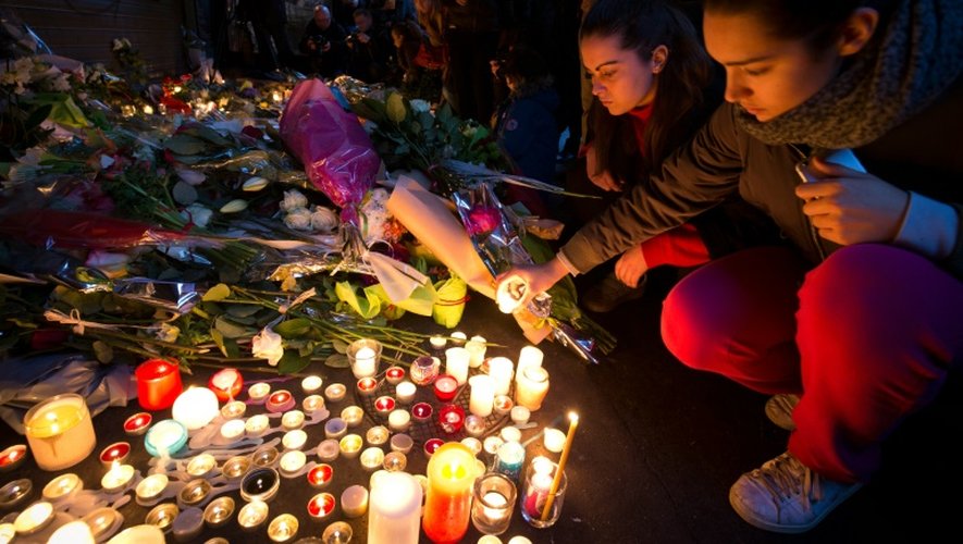 Des personnes déposent des bougies en hommage aux victimes des attentats rue de Charonne à Paris, le 14 novembre 2015