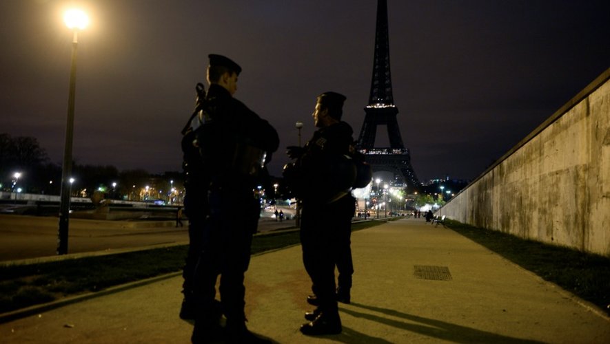 Des policiers devant la Tour Effeil éteinte en hommage aux victimes des attentats de Paris, le 14 novembre 2015