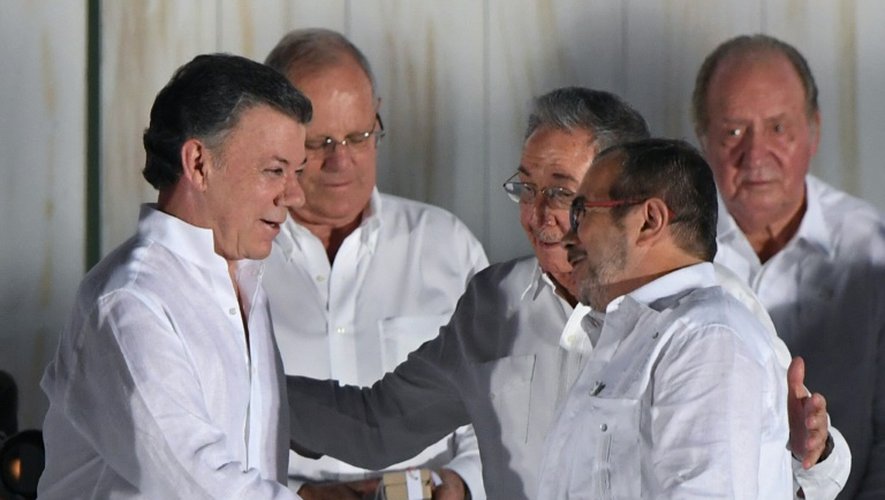 Le président cubain Raul Castro félicite le président colombien Juan Manuel Santos (G) et le leader des FARC Rodrigo Londono alias "Timochenko" (D) qui se serrent la main après la signaturz de l'accord de paix, le 26 septembre 2016