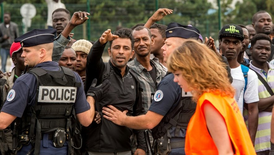 Des habitants de la "Jungle" de Calais interpellent une responsable de la préfecture chargée de sélectionner les migrants envoyés dans des Centres d'accueil et d'orientation (CAO), le 13 septembre 2016 à Calais