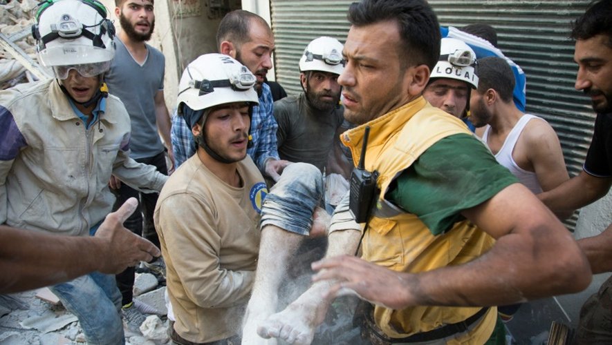 Des sauveteurs "Casques blancs" transportent le corps d'une victime tiré des décombres d'un immeuble après des bombardements, dans un quartier rebelle d'Alep, le 23 juillet 2016 en Syrie