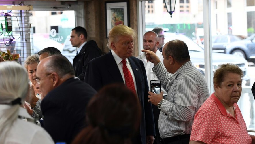 Le candidat républicain à la présidentielle américaine Donald Trump écoute un homme dans un café boulangerie à Miami, le 27 septembre 2016 en Floride