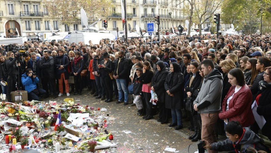 Des personnes rassemblées devant le Bataclan observent une minute de silence, le 16 novembre 2015 à Paris, après les attentats meurtriers