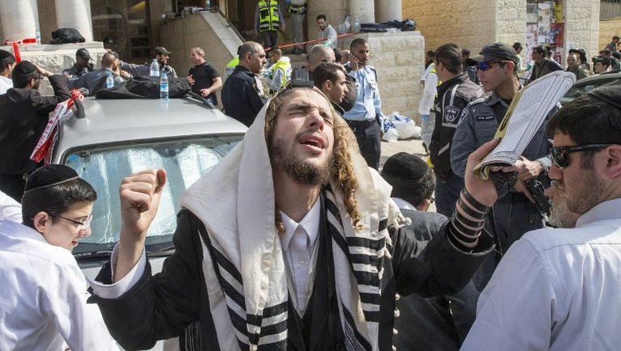 Un juif ultra-orthodoxe prie devant l'entrée de la synagogue à Jérusalem le 18 novembre 2014, quelques heures après une attaque qui a fait quatre morts parmi les fidèles