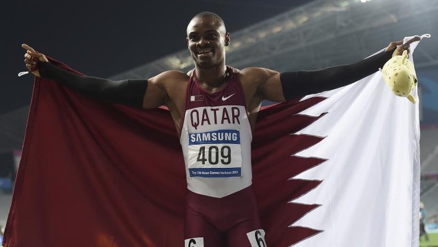 Le sprinteur qatari Femi Seun Ogunode se couvre du drapeau du Qatar après avoir remporté le 200m des Jeux Asiatiques à Incheon, le 1er octobre 2014