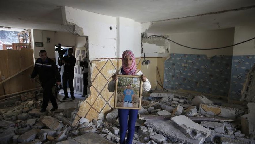 Une jeune Palestinienne montre le portrait d'Abdelrahman Shalodi, auteur d'une attaque à la voiture bélier en octobre, à l'intérieur de son appartement détruit par les autorités israéliennes, le 19 novembre 2014 à Jérusalem-Est
