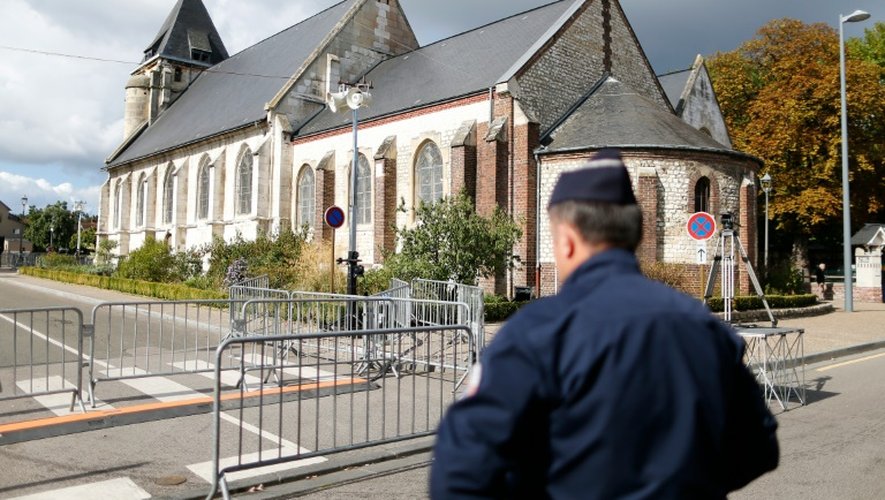 Un policier en faction derrière l'église Saint-Etienne-du-Rouvray, le 2 octobre 2016 jour de la réouverture de l'église aux fidèles