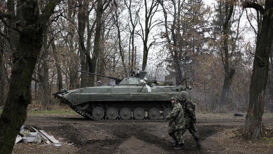 Des soldats ukrainiens marchent près d'un véhicule blindé à Peski, dans la région de Donetsk, le 19 novembre 2014 dans l'Est de l'Ukraine