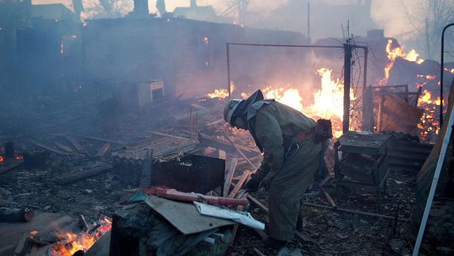 Un pompier au milieu des ruines de maisons incendiées lors d'un bombardement près de l'aéroport de Donetsk, le 20 novembre 2014 dans l'Est de l'Ukraine