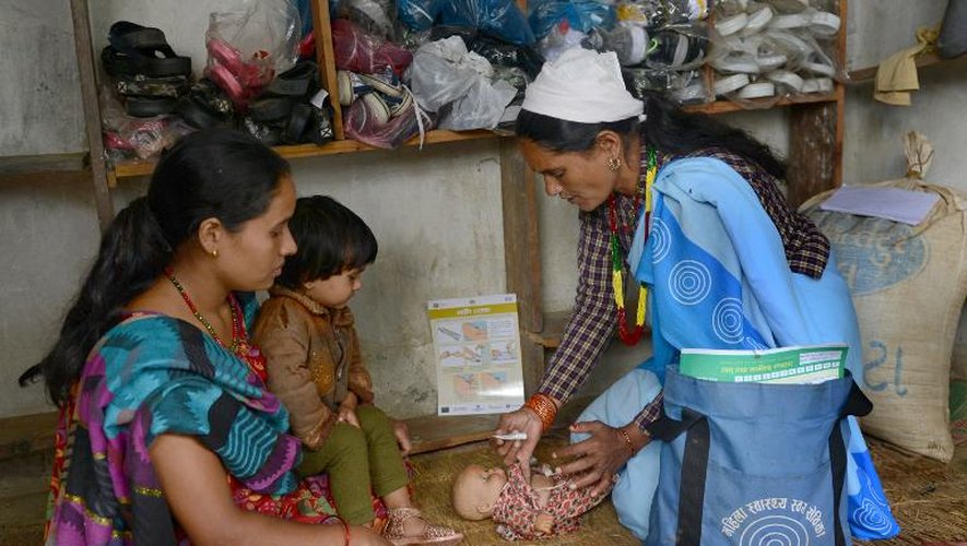 La bénévole Bhumisara Upadhyay, mère de famille népalaise (d)conseille une femme enceinte à son domicile à Barlamgi, à quelque 600 km à l'ouest de Katmandou, sur les soins à apporter au nouveau-né, le 11 septembre 2014