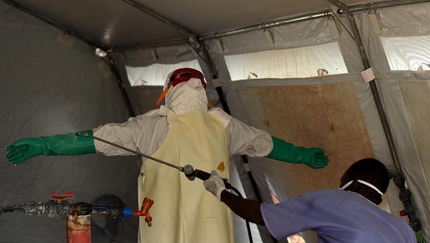 Une infirmière est désinfectée après avoir été en contact avec des malades d'Ebola au centre de traitement de Kenama (Sierra Leone) dirigé par la Croix rouge, le 15 novembre 2014