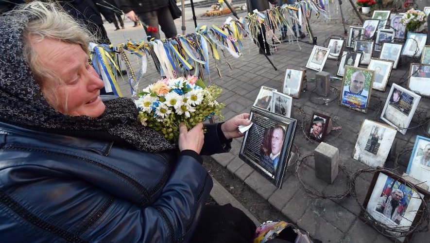 Une femme vient déposer des fleurs devant un portrait de son fils au monument pour les victimes du Maïdan, le 21 novembre 2014 à Kiev
