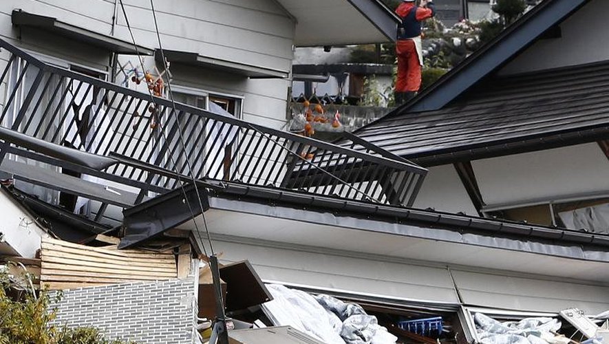 Un secouriste sur le toit d'une maison effondrée après un tremblement de terre, le 23 novembre 2014 à Hakuba, dans la préfecture de Nagano, au Japon