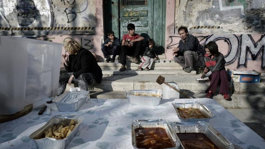 Des familles d'immigrés et des squatters grecs, partagent un repas préparé par une "cuisine sociale", le 2 novembre 2014 au complexe "Ta Prosfygika" à Athènes