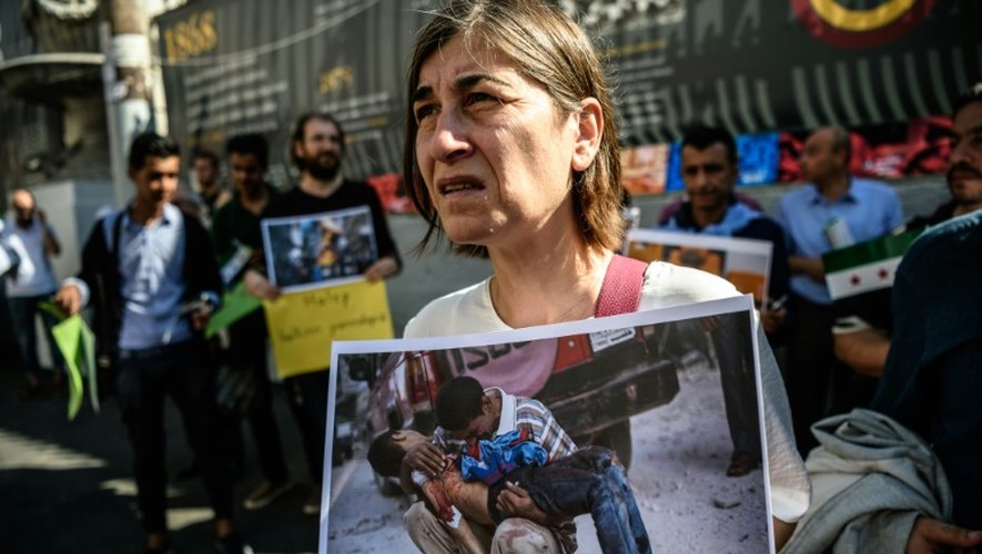 Une manifestante montre une photo de la guerre en Syrie lors d'un rassemblement à Istanbul destiné à protester contre les bombardements du régime syrien et de ses alliés sur Alep, le 1er octobre 2016