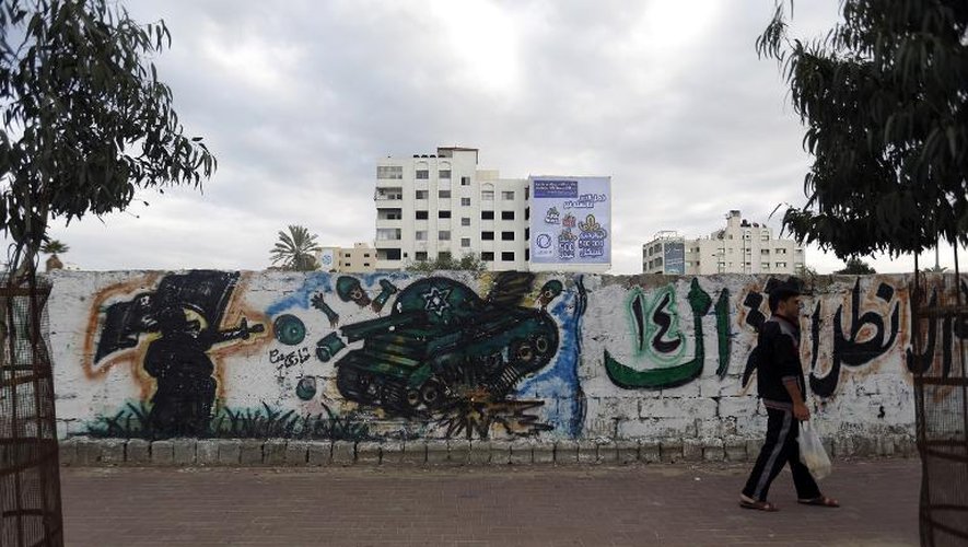 Un homme passe devant un mur de graffiti représentant un manifestant et un char israélien, le 21 novembre 2014 à Gaza