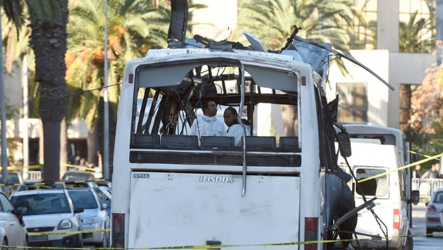 Des enquêteurs de la police scientifique relèvent des indices sur la carcasse d'un bus de la sécurité présidentielle cible d'un attentat à la bombe en plein centre de Tunis, le 25 novembre 2015