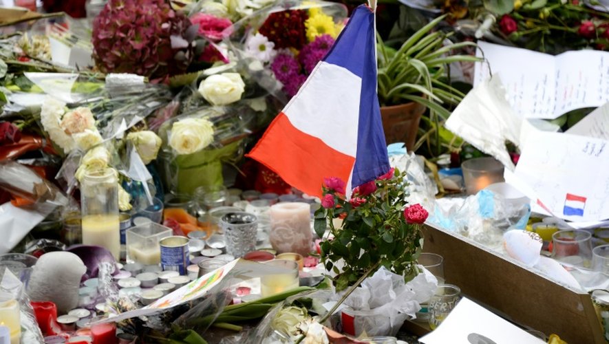 Un drapeau français parmi les fleurs et bougies déposées devant la salle du bataclan à Paris le 16 novembre 2015