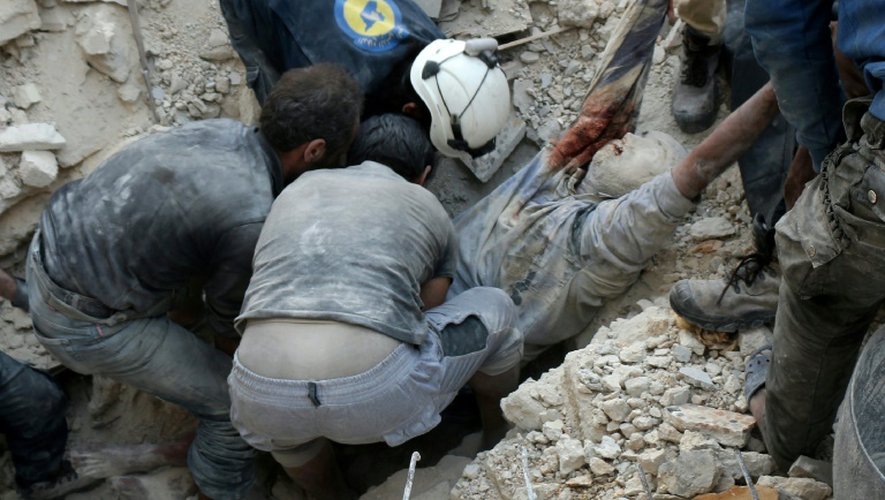 Des Syriens sauveteurs volontaires dénommés Casques blancs récupèrent des blessés et des morts après des bombardements aériens sur un quartier nord de Alep, le 4 octobre 2016