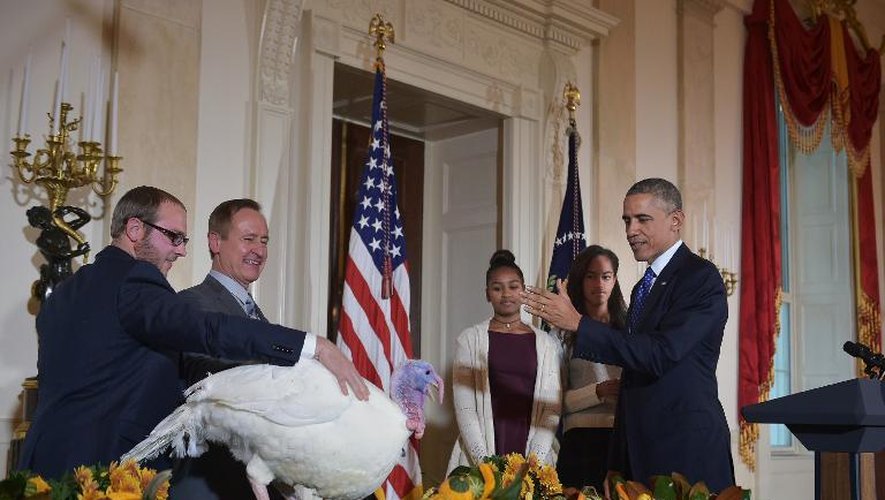 Le président américain Barack Obama, ses deux filles Sasha (c) et Malia (2e à d) à ses côtés, gracie une dinde nommée "Cheese" à la Maison Blanche à Washington, le 26 novembre 2014