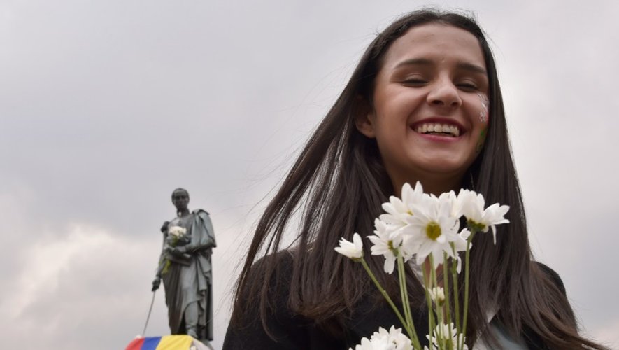 Une jeune Colombienne célèbre, un bouquet de fleurs à la main, le prix Nobel de la Paix sur la place Simon-Bolivar à Bogota, le 7 ocotbre 2016