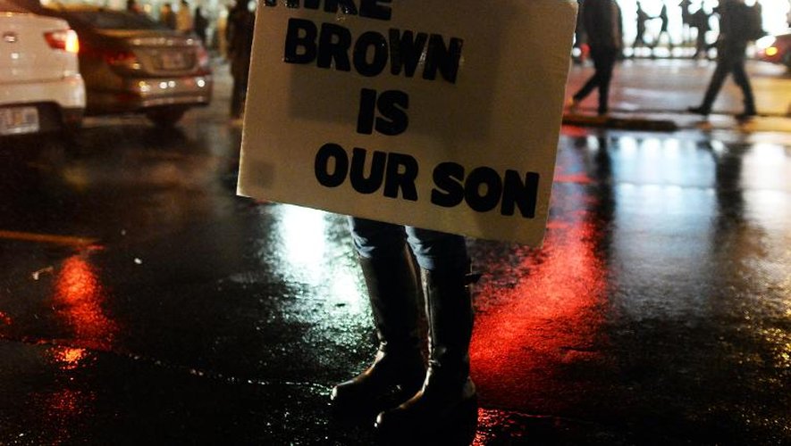 Un manifestant tient un panneau "Mike Brown est notre fils" dans une rue de Ferguson, le 26 novembre 2014 dans le Missouri