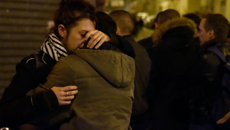 Des gens se rassurent mutuellement lors d'un rassemblement devant le Carillon, à Paris, le 15 novembre 2015