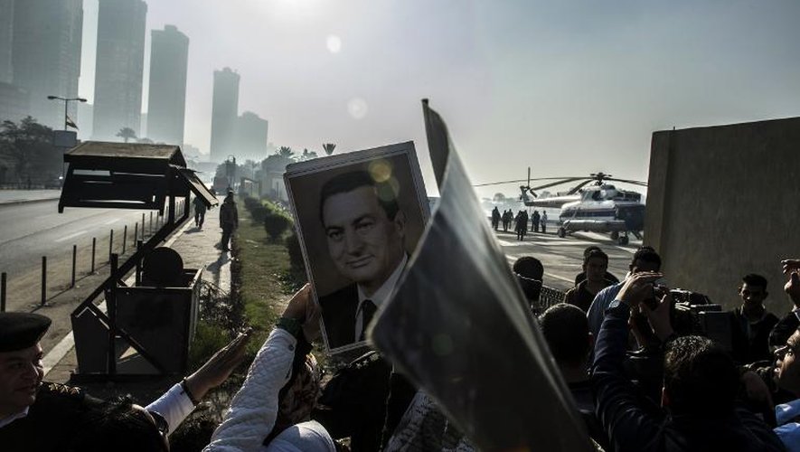 Des partisans de l'ancien président égyptien Hosni Moubarak brandissent des portraits du raïs, quand son convoi médicalisé quitte l'hôpital militaire de Maadi pour se diriger vers un tribunal au Caire où a lieu son procès le 29 novembre 2014