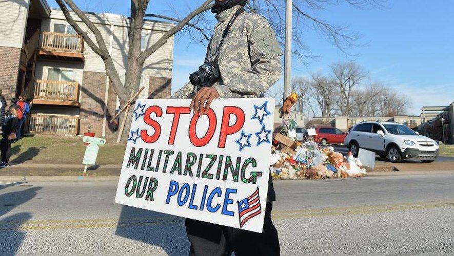 Un homme porte un pancarte demandant l'arrêt de la "militarisation" de la police, lors d'une manifestation à Ferguson (Missouri) le 29 novembre 2014, en mémoire au jeune Noir tué par un policier en août