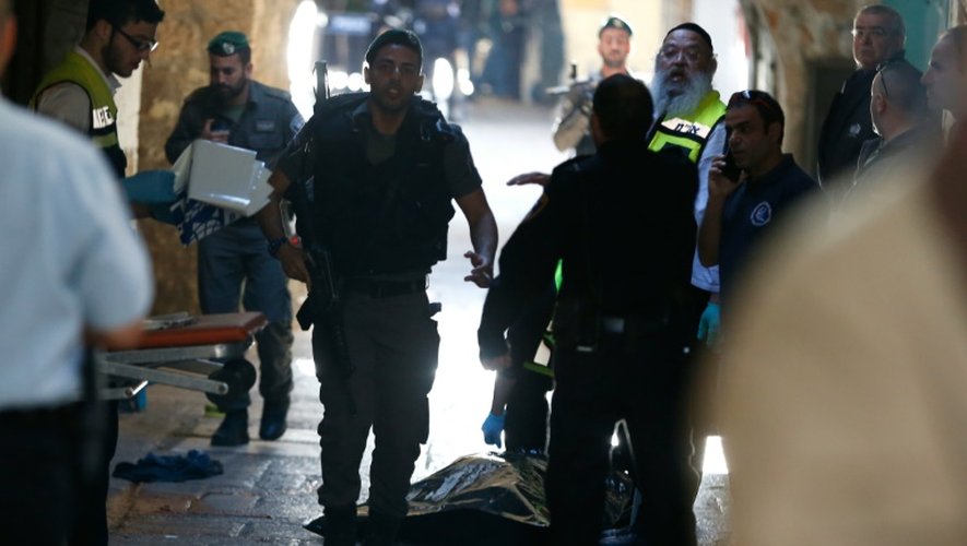 Des membres des forces de sécurité et du personnel médical israéliens près du corps de l'assaillant palestinien tué après qu'il eut blessé au couteau un garde-frontière israélien dans la vieille ville de Jérusalem, le 29 novembre 2015