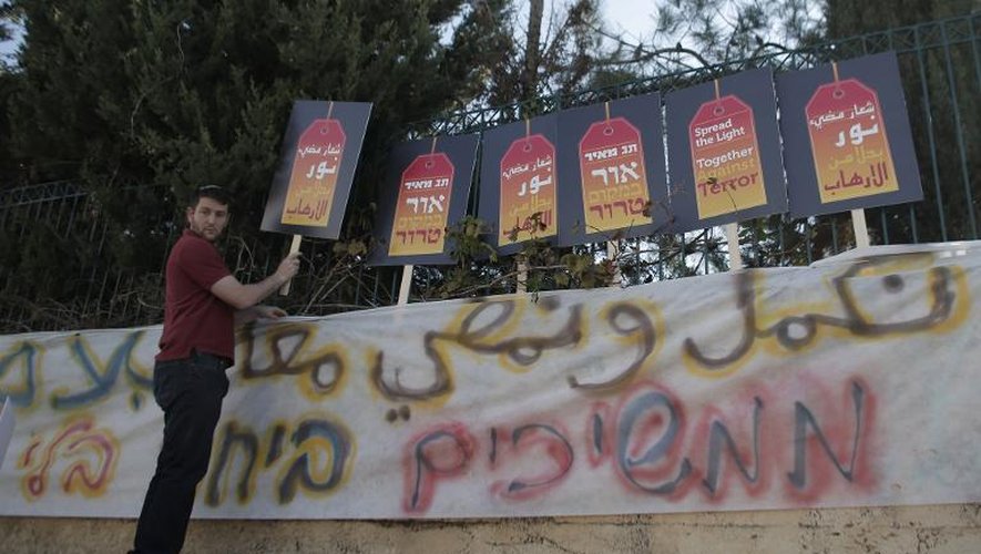 Un isralien tient une pancarte sur laquelle est écrit "Ensemble contre la terreur" lors d'un rassemblement devant une école bilingue arabe-hébreu à Jérusalem qui a été incendiée et taguée d'inscriptions anti-Arabes, le 30 novembre 2014