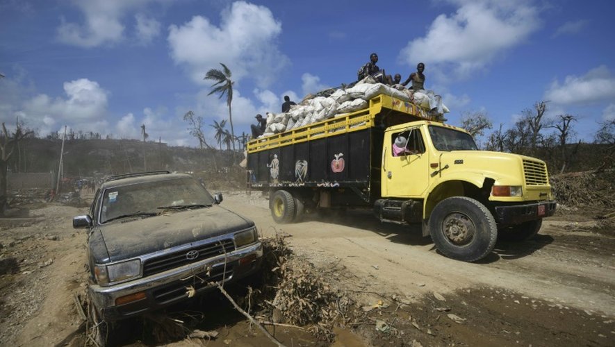 Des habitants juchés sur un camion le 10 octobre 2016 dans une rue dévasté de Jeremi à l'ouest de Port-au-Prince