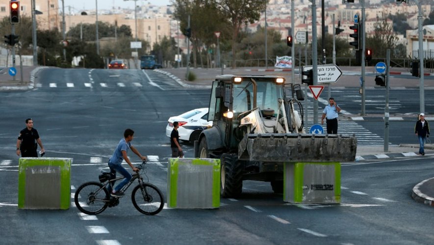 Un policier israélien monte la garde au moment où les forces de sécurité israéliennes installent des blocs de ciments sur une route séparant Jérusalem-est et Jérusalem-ouest le 11 octobre 2016
