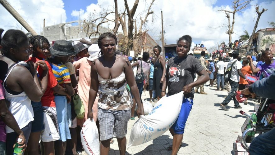 Des victimes de l'ouragan Matthew transportent un sac de nourriture distribué par le Programme alimentaire mondial, le 12 octobre 2016 en Haïti