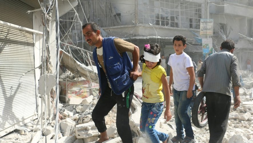 Des Syriens marchent sur des décombres après des raids aériens sur le quartier Fardous de Alep, le 12 octobre 2016.