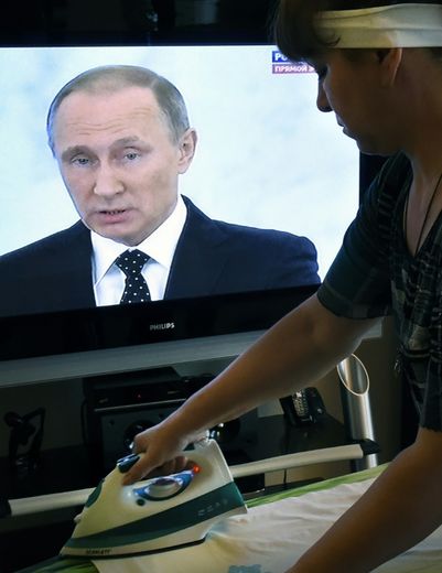 Une femme au foyer repasse en regardant l'intervention télévisée à Moscou le 3 décembre 2015