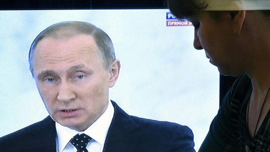 Une femme au foyer repasse en regardant l'intervention télévisée à Moscou le 3 décembre 2015